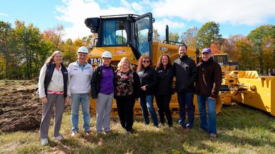 Alfred University administration smiling in front of a bulldozer